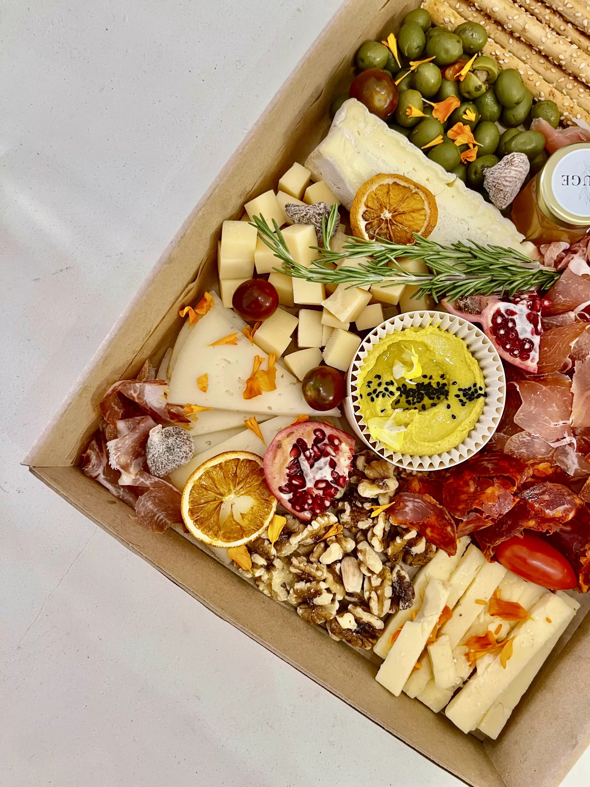 Cheese and charcuterie grazing box in Marbella with dried orange, pomegranate, hummus and Iberian chorizo