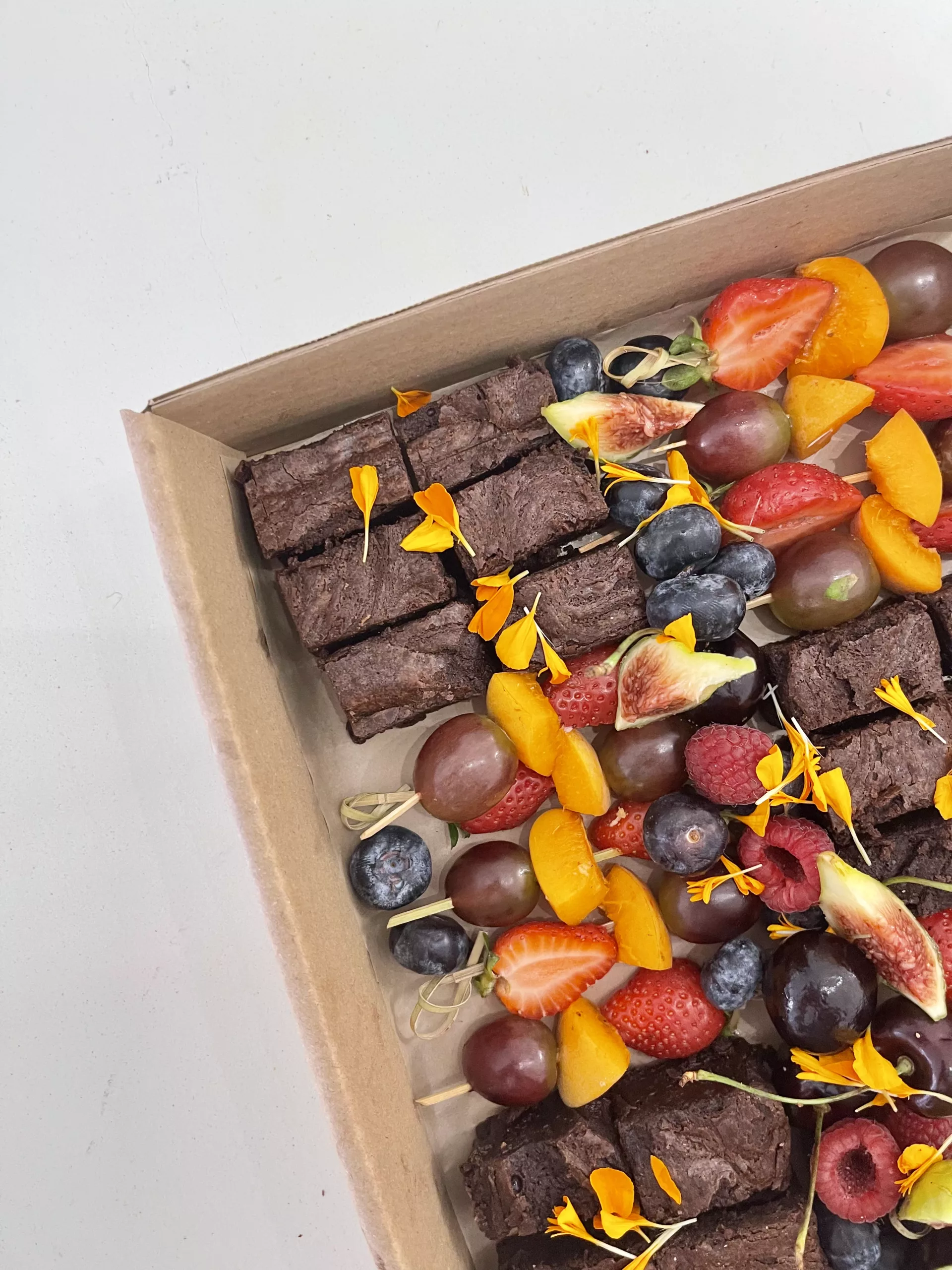 Brownies Sauge Marbella con brochetas de fruta fresca, arandanos y flores comestibles
